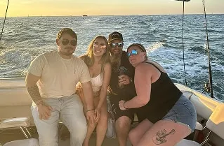 Four guests relaxing on the deck of Captain Rio's boat as the sun sets over the water off Key West