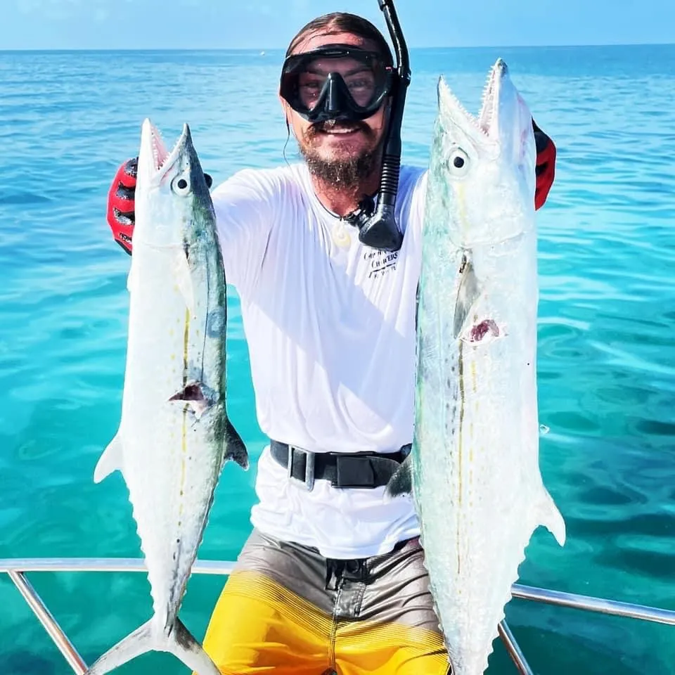 Spearfisherman in mask and snorkel holding two kingfish speared in the clear water off Key West